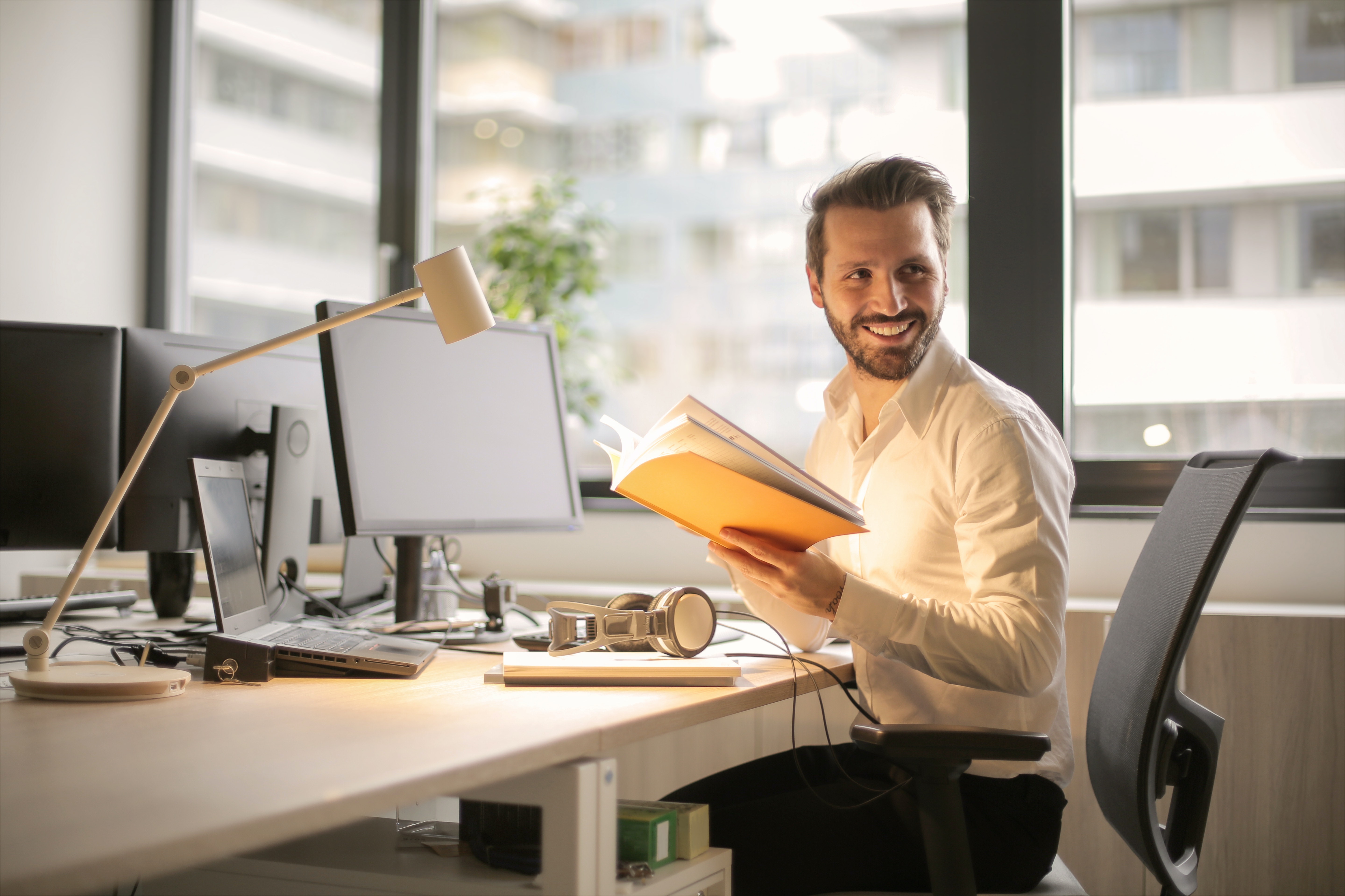 man happy at his desk holding a book